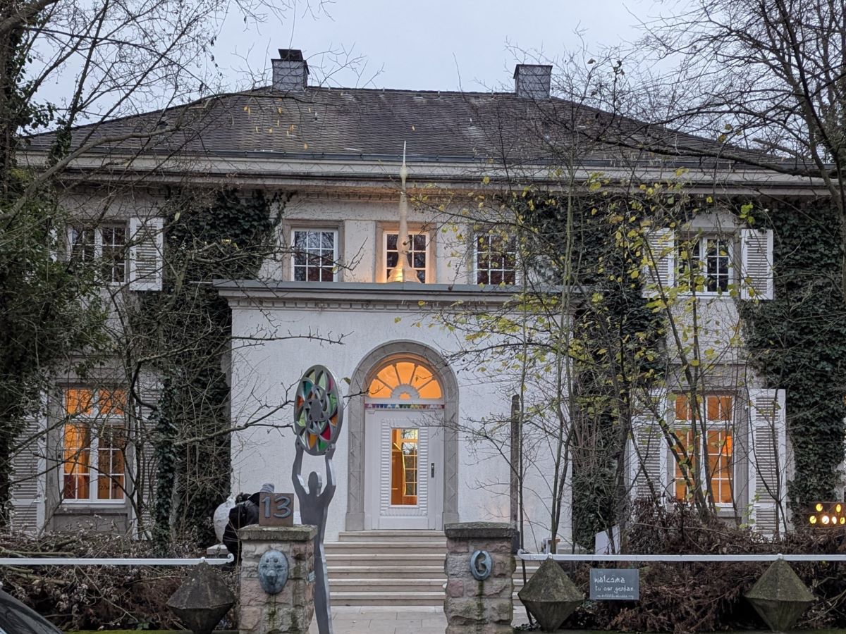 Außenansicht der Villa Martinus, ein beeindruckendes Gebäude mit historischem Charme, umgeben von üppigem Grün im Vortex Garten in Darmstadt